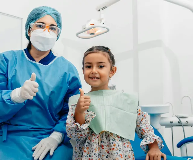 Una bambina e la dentista alzano il pollice in poltrona